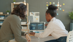 Two people looking at data on a laptop screen and discussing digital information in an office environment.