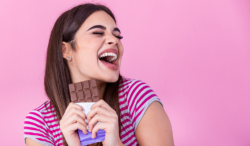 A young woman holds a bar of chocolate in her hand.